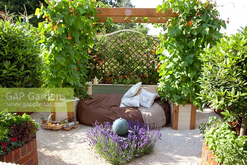 Seating area in vegetable garden with Lavandula 'Hidcote' surrounding a solar-powered water feature and Runner Beans in pots. 'Food for Thought' - Silver Gilt Medal Winner - RHS Hampton Court Flower Show 2010 