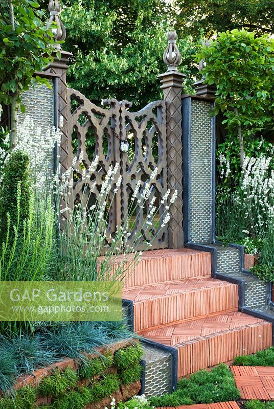 Herringbone tile steps lead up to a carved wooden gate, with rainbow effect water features, plants include Lavandula angustifolia 'Alba', Koeleria glauca and Armeria maritima 'Alba'. 'The Garden Lounge' - Silver Gilt Medal Winner - RHS Hampton Court Flower Show 2010 
 