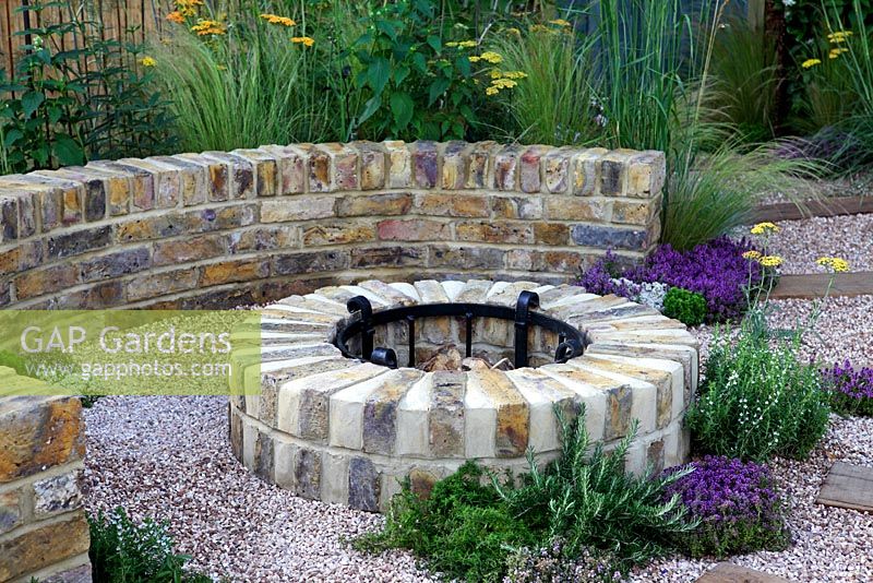 Curved gravel patio area with Stipa tenuissima, Achillea 'Terracotta', Thymus, Rosemarinus officinalis Prostatus Group. 'The Fire Pit Garden' - Silver Medal Winner - RHS Hampton Court Flower Show 2010 
 