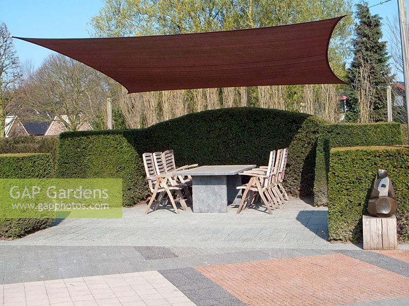 Seating area under canopy bordered by clipped Taxus - Yew hedge. Netherlands
