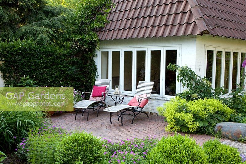 Large summerhouse and patio in the corner of country garden
