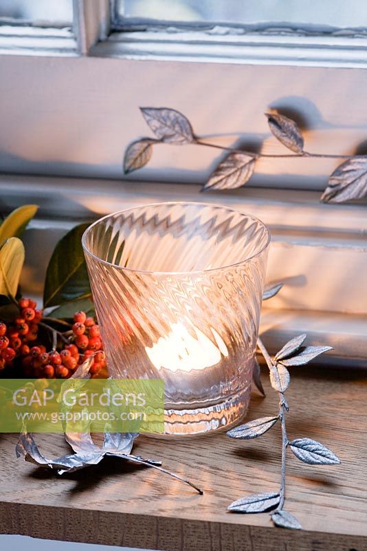 Silver sprayed leaves used as a festive decoration with a vintage glass tealight holder