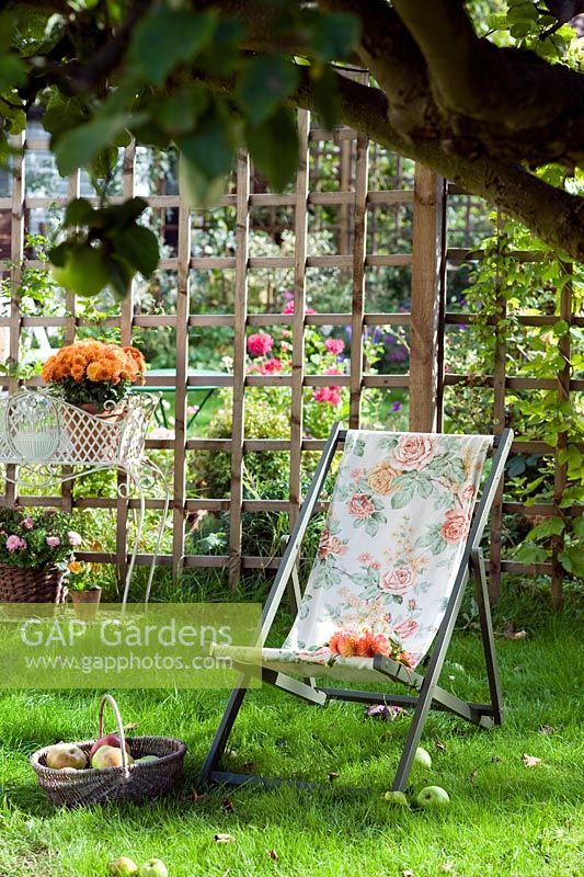 Deckchair on lawn and a bunch of orange Dahlias 
