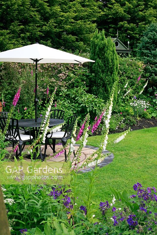 Circular seating area with table, chairs and umbrella, surrounded by colourful borders