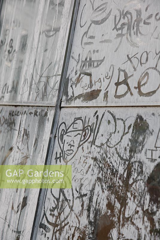 Glasshouse with graffiti in dust at Petersham Nurseries, Richmond, Surrey 