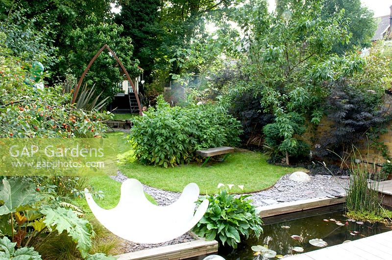 Urban garden showing resin water feature, rectangular pond and curved slate path under metal arch. Yulia Badian garden, London, UK