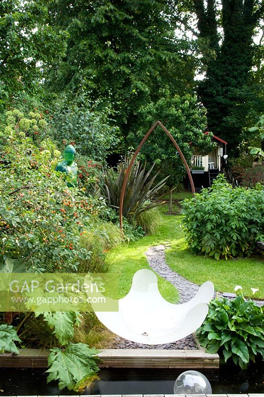 Urban garden showing resin water feature, rectangular pond and curved slate path under metal arch. Yulia Badian garden, London, UK