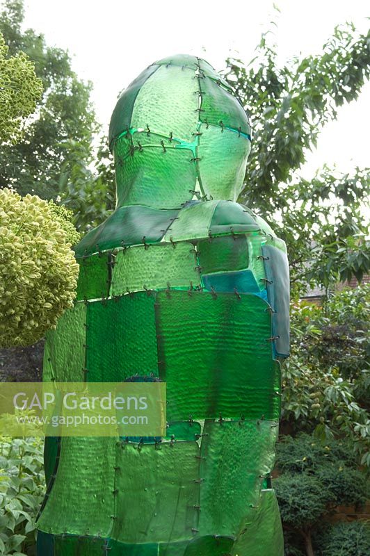 Rear view of green resin figure in border. Yulia Badian garden, London, UK 