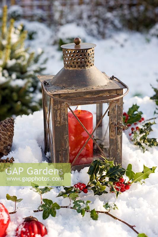 Lantern with red candle, Holly and Ivy on snowy table