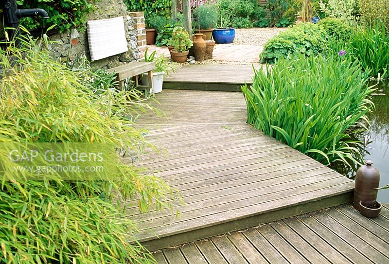 Shallow wooden steps beside pond in late Spring. Fovant Hut Garden, Wilts