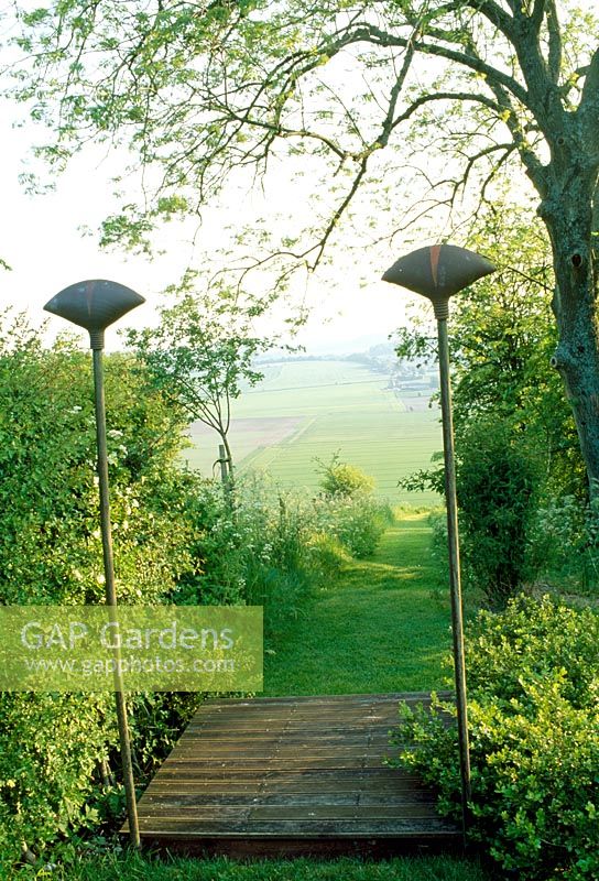 Path down side of garden, with view framed by finial-topped posts. Late Spring, Fovant Hut Garden, Wilts. 