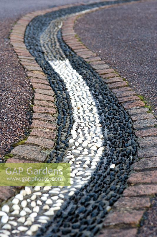 Drainage channel inlaid with black and white pebbles