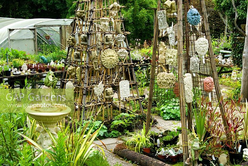 Plants in the nursery sales area are interspersed with sculptural figures, plaques and furniture - Pinsla Garden, Cardinham, Cornwall