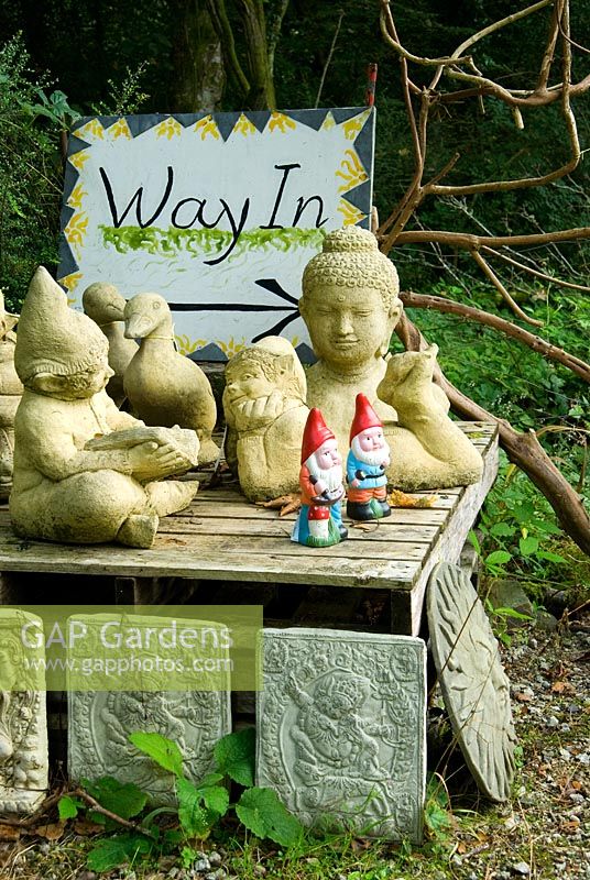 Plants in the nursery sales area are interspersed with sculptural figures, plaques and furniture - Pinsla Garden, Cardinham, Cornwall