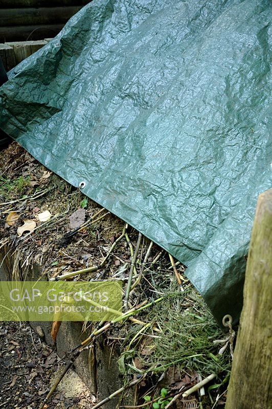 Compost bin covered with sheet to build heat and quicken composting