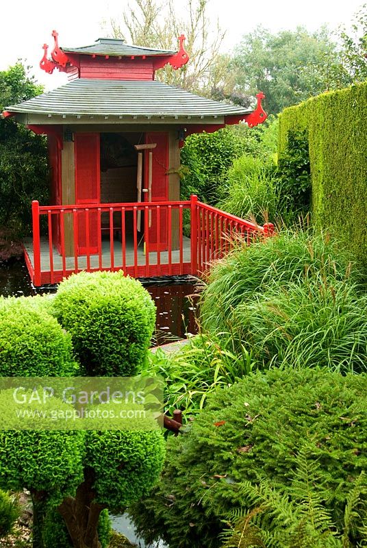 Japanese tea house with pond framed by cloud pruned conifers. The Croft, Yarnscombe, Devon, UK