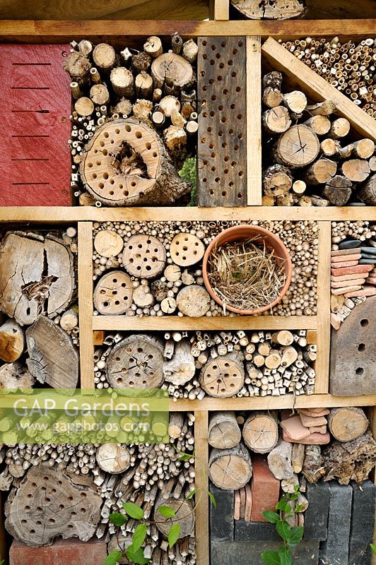 Insect house made from logs, bamboos and straw in clay pot