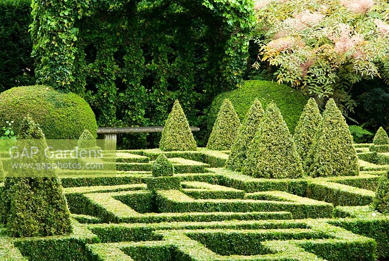 Hedera - Ivy covered port-cullis shaped gazebo at the end of the Knot Garden of clipped Buxus - Box. Bourton House, Bourton-on-the-Hill, Moreton-in-Marsh, Glos, UK