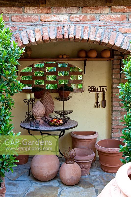Display of terracotta and decorative metal objects on a bistro table in a gangway. Laurus nobilis