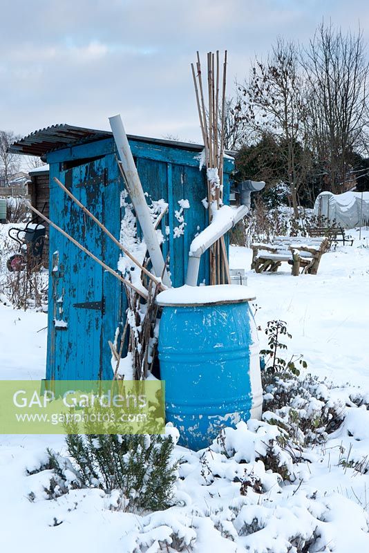 Painted blue shed and water butt on allotment in winter