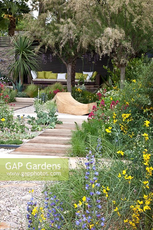 Seating area with curved timber bench and salt tolerant planting including Crambe maritima - Sea Kale, Armeria - Thrift, and Centranthus ruber - The Cancer Research UK Garden, Silver Gilt Medal Winner, RHS Chelsea Flower Show 2011 