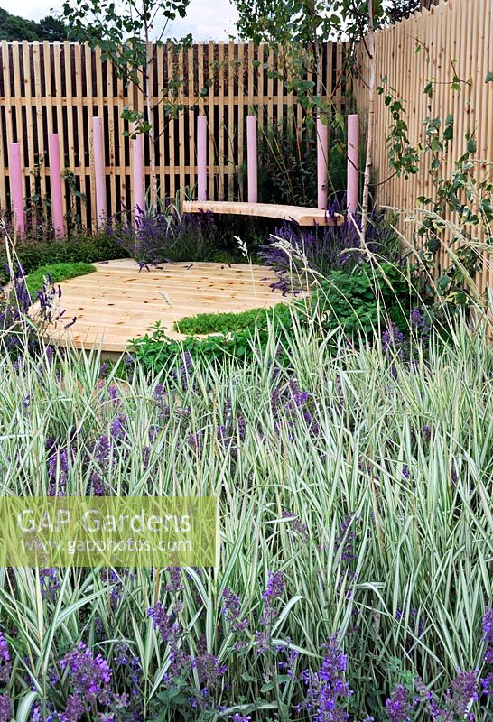 Garden planted with swathes of Phalaris arundinacea 'Feesey', and Nepeta 'Six Hills Giant'. Raised seating area with pink timber posts surround - RHS Tatton Park Flower Show 2011
 