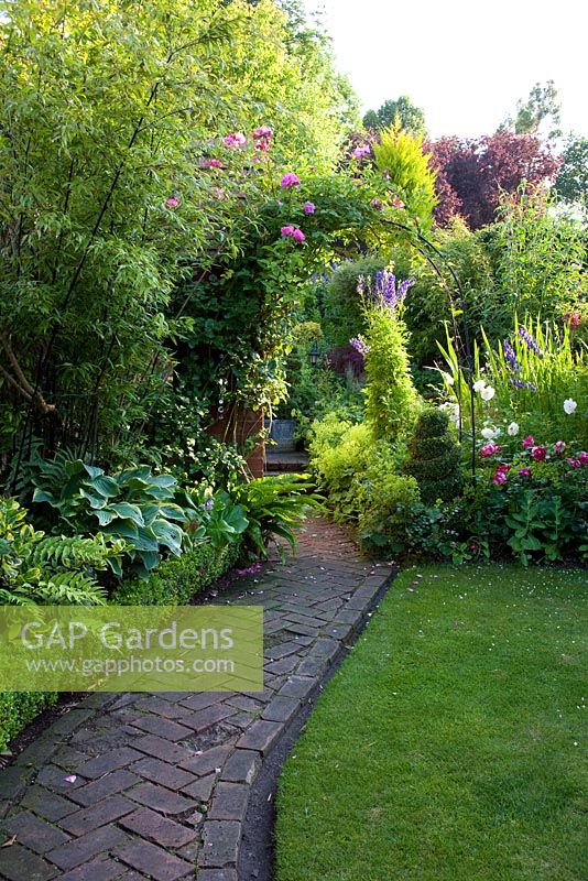 Old brick path with herringbone patten leads up cottage garden - Merlin House, Wiltshire, UK 