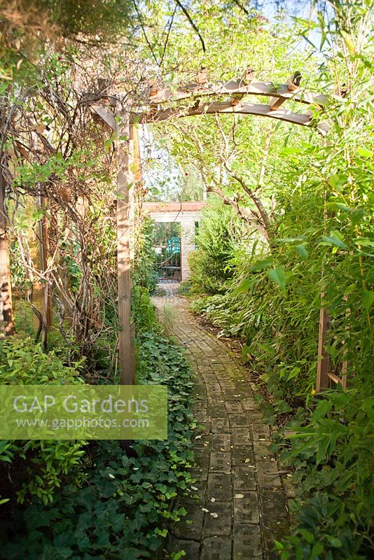 Paved path under wooden archway towards the entrance to the garden, Garden Hackl, Mistelbach Austria