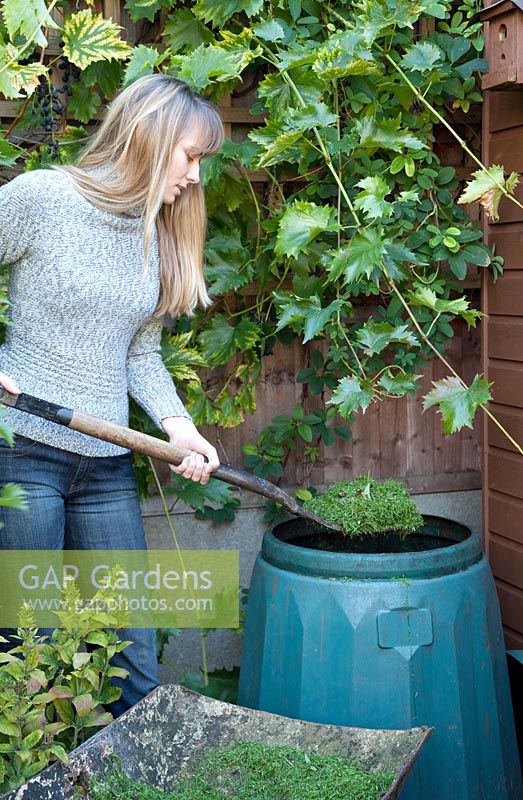 Woman filling compost bin with lawn cuttings