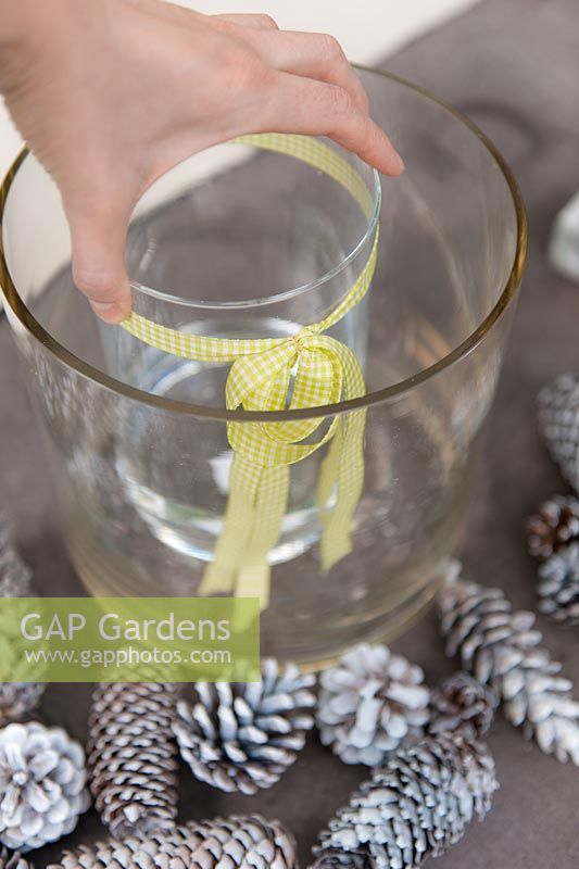 Making winter flower arrangement with Pine cones and glass beaker