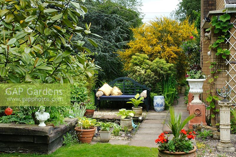 Terrace with ornamental pond, blue painted Lutyens style bench and raised bed made with railway sleepers - The Rowans, Threapwood, Cheshire.
