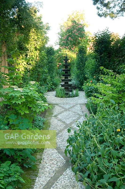Concrete and cobblestone pebble path and water fountain. Planting includes Phlomis Citrus and Aesculus - Madrid, Spain 

