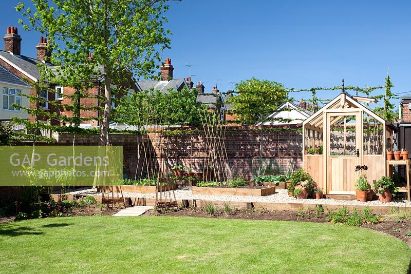 Garden overview with wooden greenhouse and raised vegetable beds 