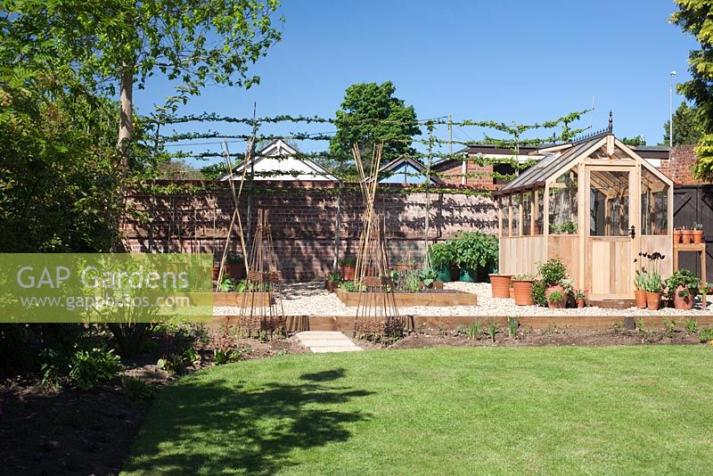 Garden overview with wooden greenhouse and raised vegetable beds 