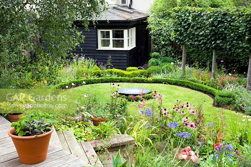 View from raised deck across border, lawn and house - Brook Hall Cottages, Essex NGS