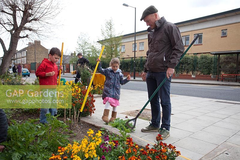 Man and children tidying the Edible Bus Stop