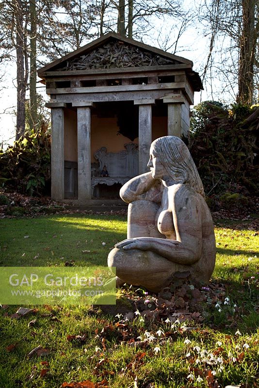 'Goddess of the Woods' sculpture and one of the two green oak temples in the Stumpery, Highgove Garden, February 2011. 