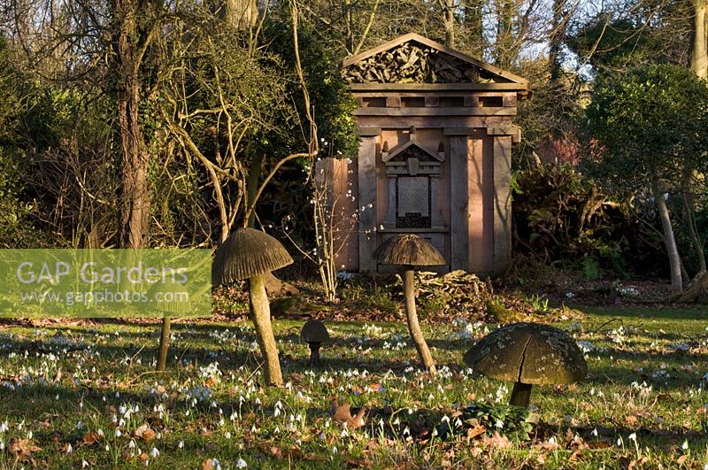 Wooden toadstool sculpture and green oak temple with snow drops in the Stumpery, February 2011.