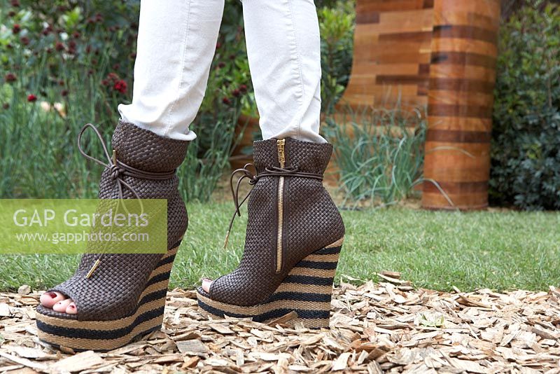 Woman wearing heels that resemble Joe's wooden structures - Homebase Teenage Cancer Trust Garden. Gold Medal Winner, RHS Chelsea Flower Show 2012