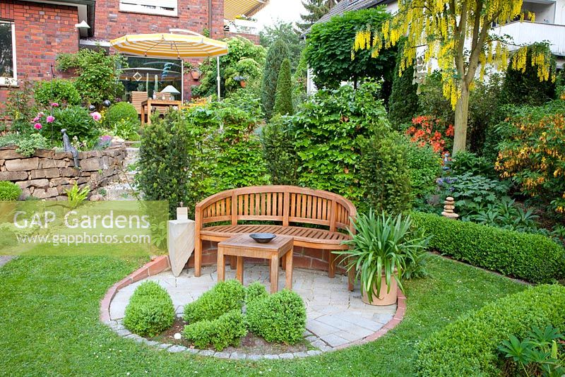Circular patio with wooden bench and box topiary