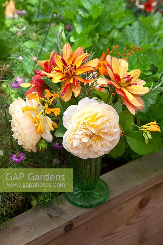Mixed Dahlias, Roses and Crocosmia in vintage glass vase in the garden