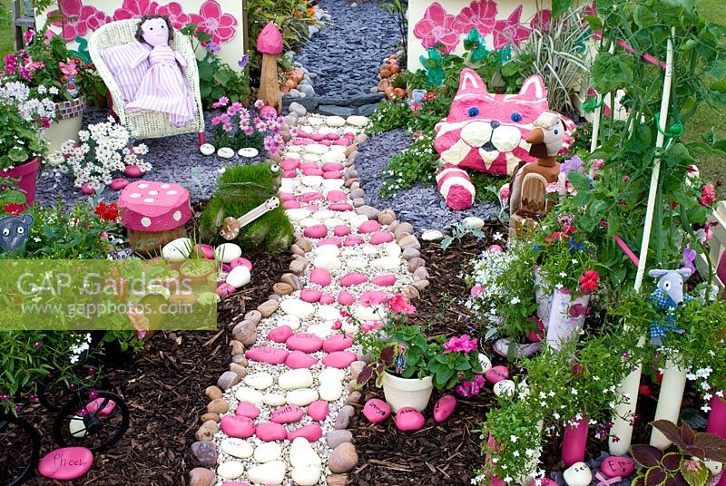 Fun, pink and white colourful garden with path and seating area. 'The Bagpuss garden' made by pupils at Thelwall Community Infant School in Warrington. RHS Tatton Flower Show 2012