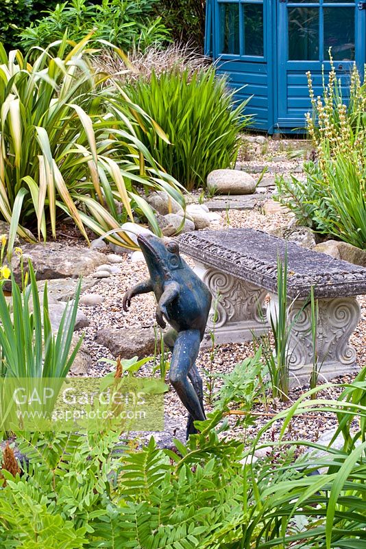 Frog fountain and stone bench in pond area, planting includes Kniphofia 'Dorset Sentry', Osmundo regalis, Phylostachys nigra and Phormium 'Yellow Wave'