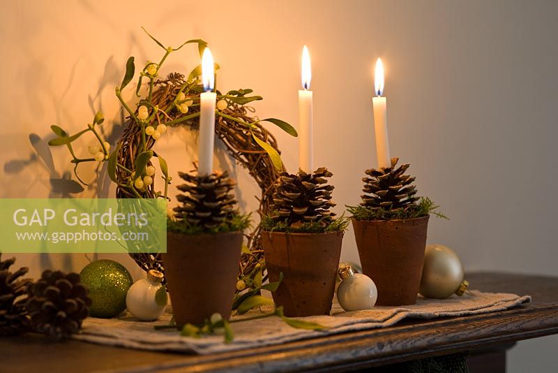 Candles with terracotta holders decorated with fir cones and moss