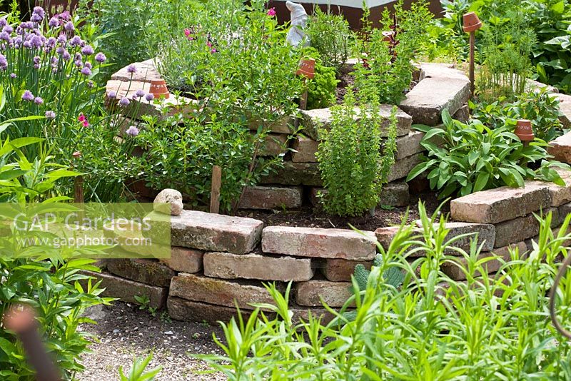 Herb spiral made of bricks with Allium schoenoprasum, Lavandula, Origanum, Salvia officinalis