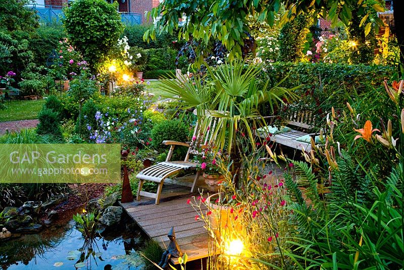 Wooden deck and seating area overlooking pond at dusk