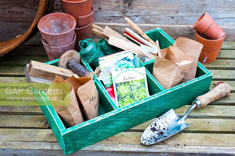 Spring time potting bench with wooden tray of gardening equipment including packets of seeds, wooden seed labels and garden twine