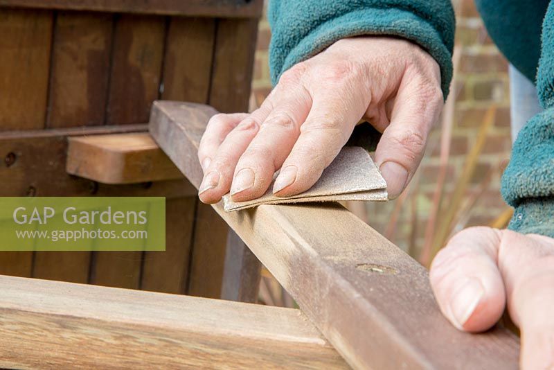 Sanding wooden seat in preparation for paint