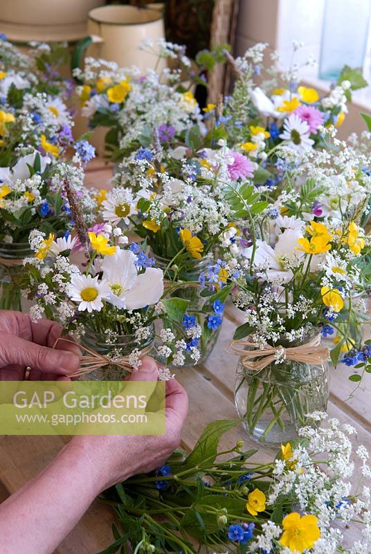 Jars of wild flowers prepared as table centres for garden party