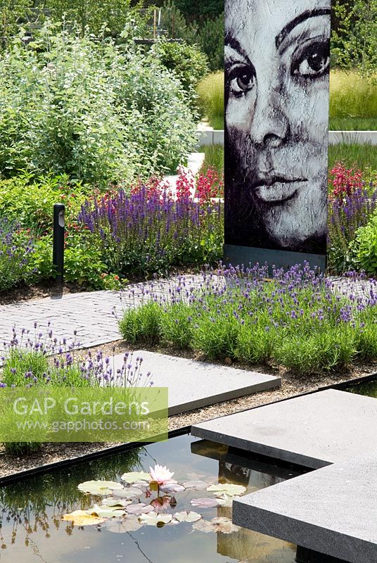 Modern garden pool with step and sculptural feature of a woman's face, with planting of Lavender, Salvia and Penstemon - Floriade 2012